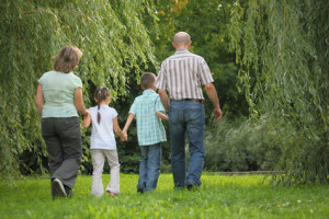 family with two children in early fall park. they are walking away.